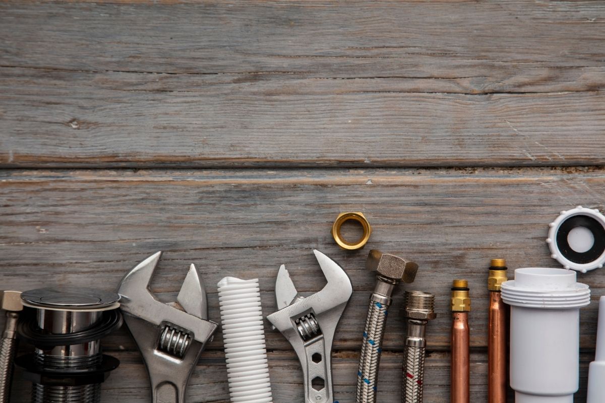 A collection of plumbing tools, including wrenches and pipes, arranged neatly on a wooden table surface.